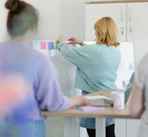 Eine Mitarbeiterin bringt Haftnotizen an ein Whiteboard an – aufgenommen während eines Teamworkshops in Hannover.